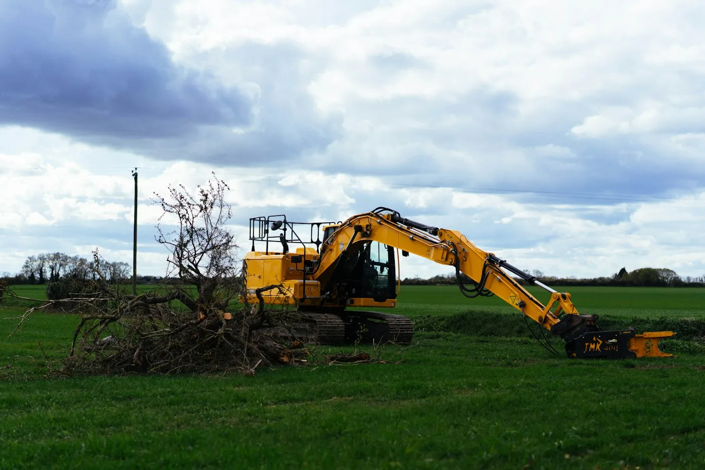 Excavator working beside grassy ground
