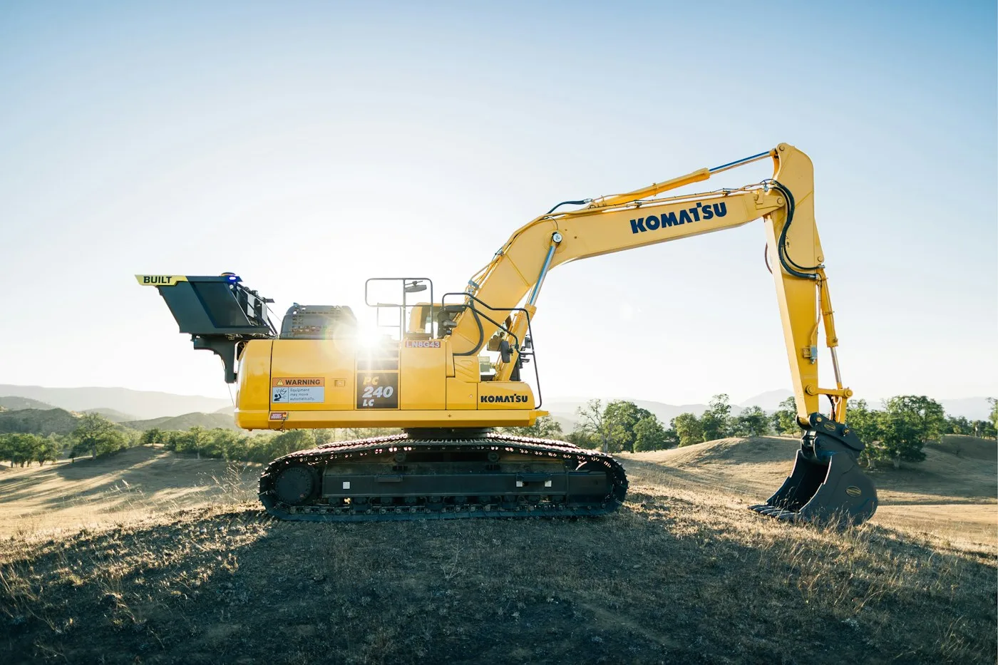 Excavator and bucket on gravel at sunset