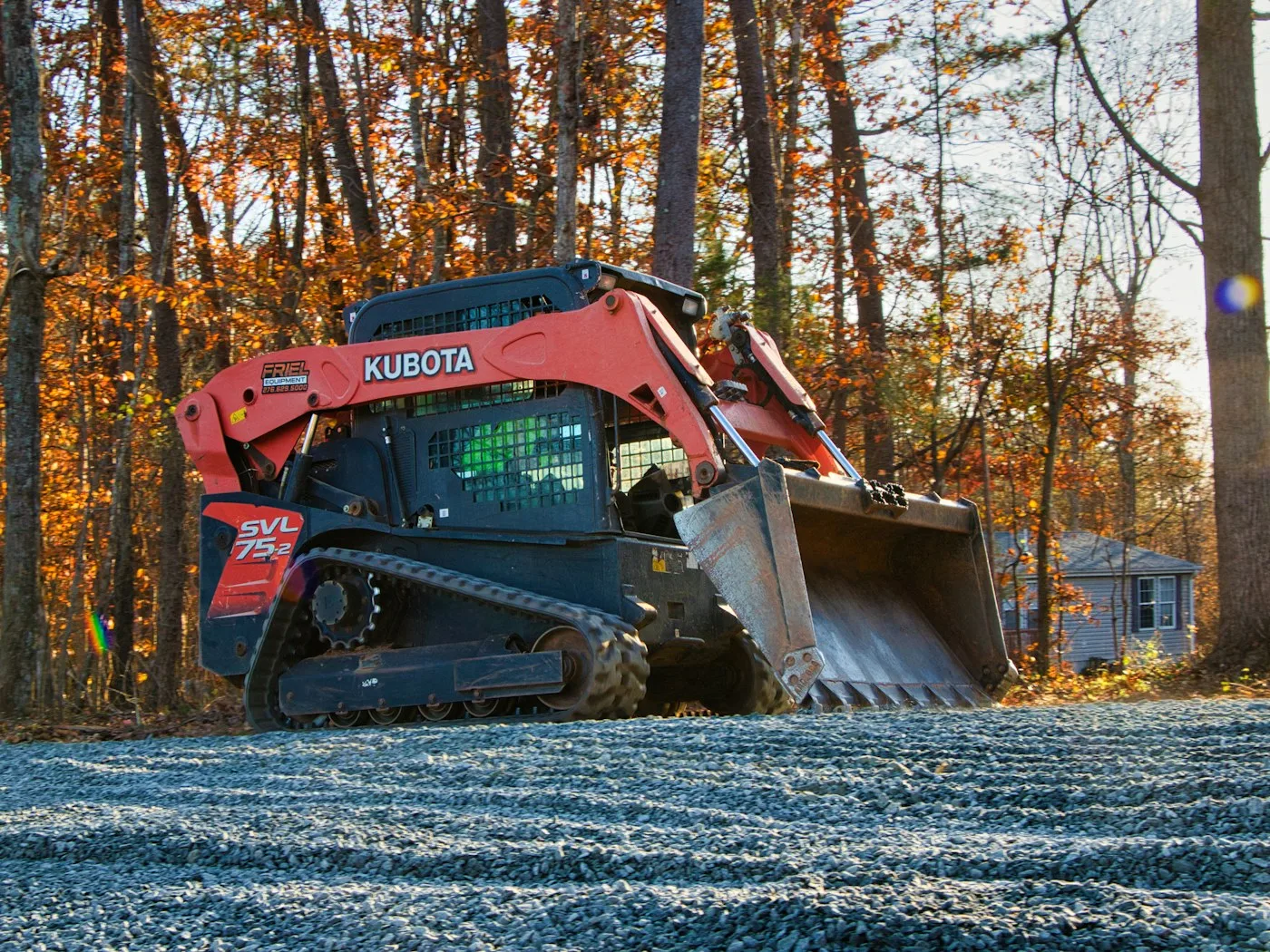 Compact tracked loader beside autumn trees